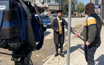 Does this young man work in shoe dyeing in Damascus, wearing a graduation uniform?